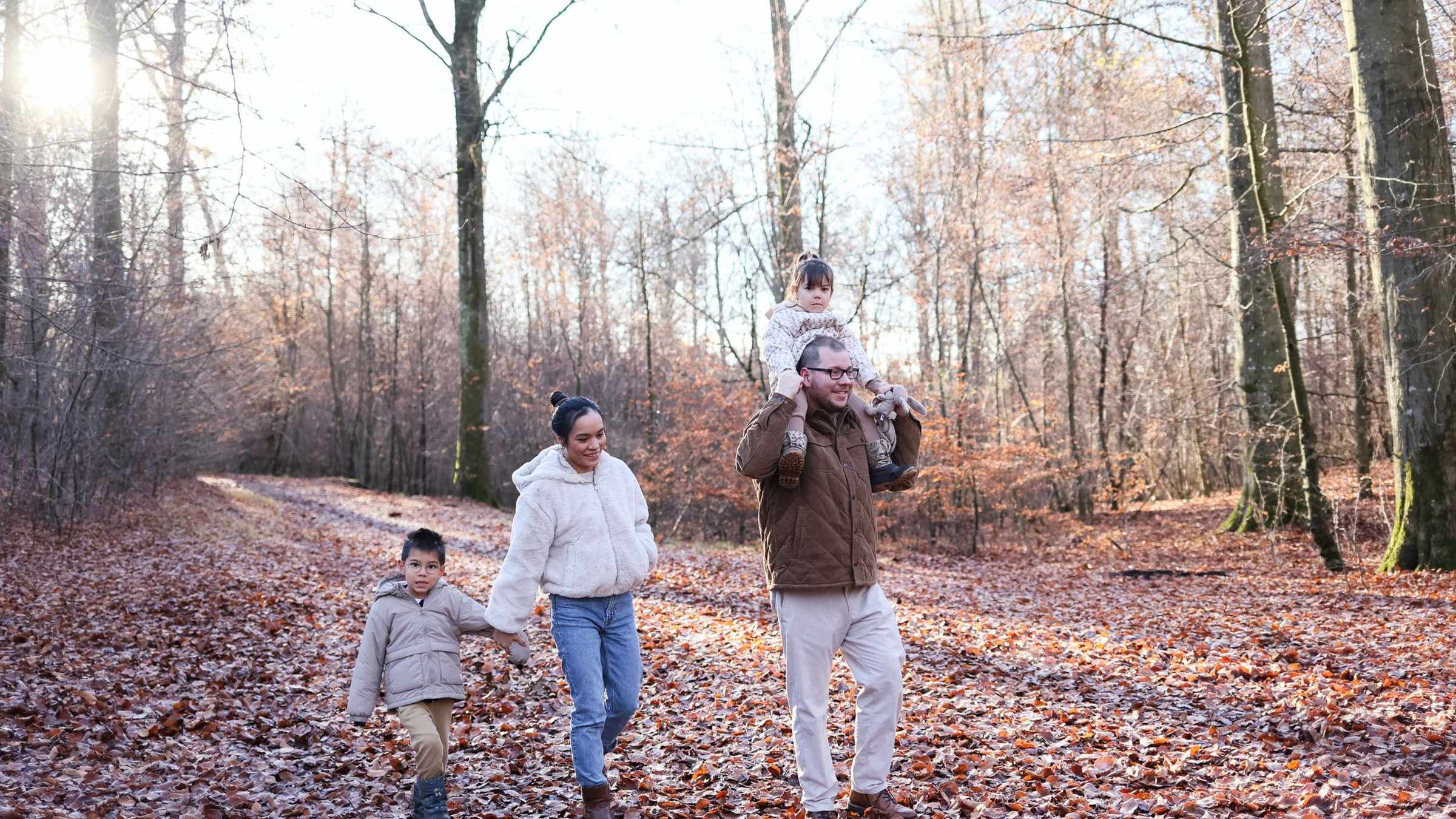 Une famille marche ensemble dans un sentier couvert de feuilles d'automne